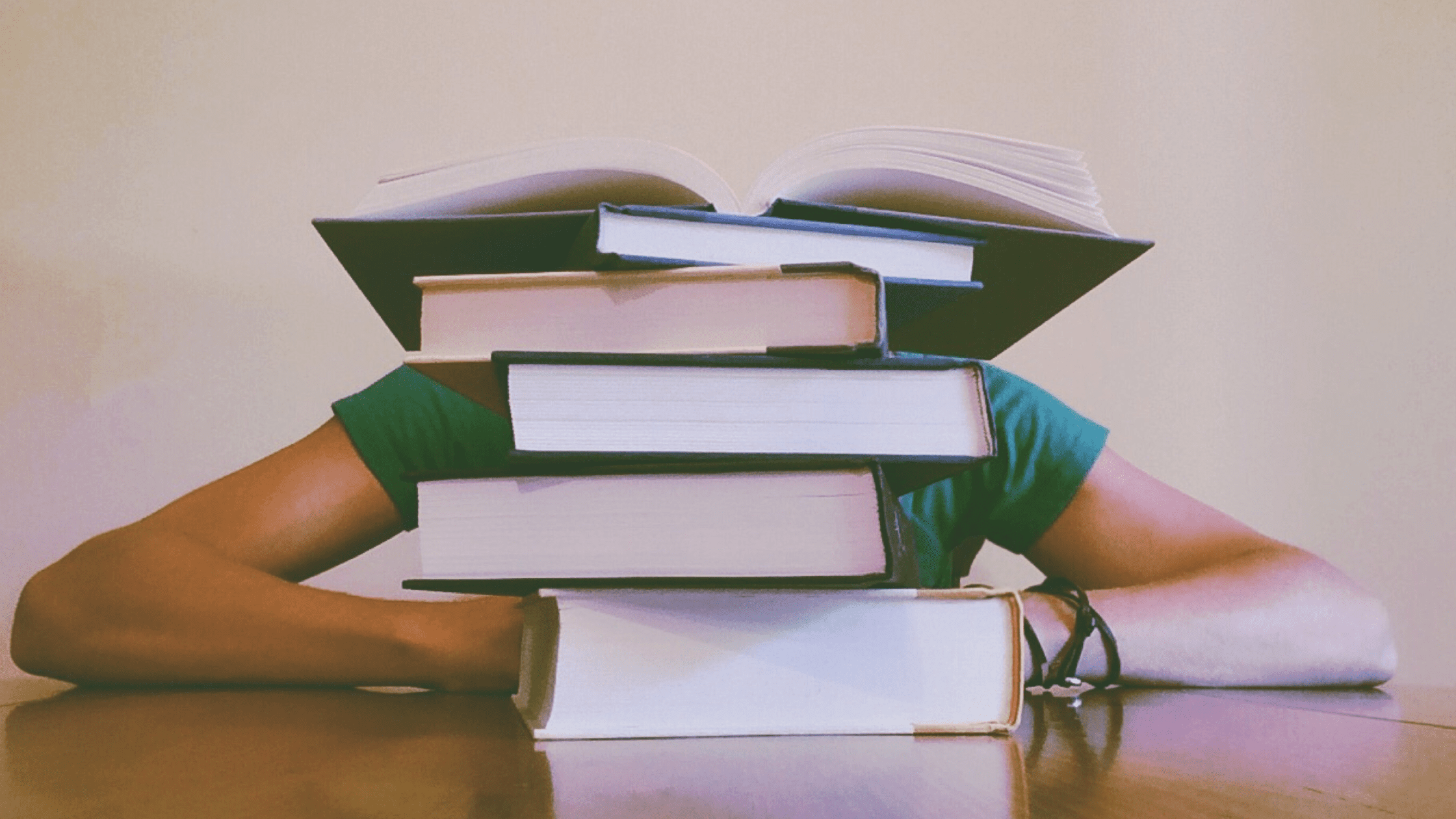A student behind a huge pile of books studying for USMLE Step 1